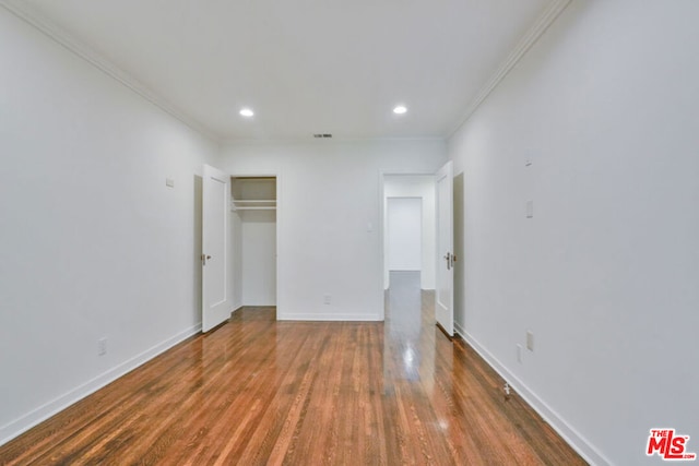 unfurnished bedroom featuring crown molding, a closet, and dark wood-type flooring