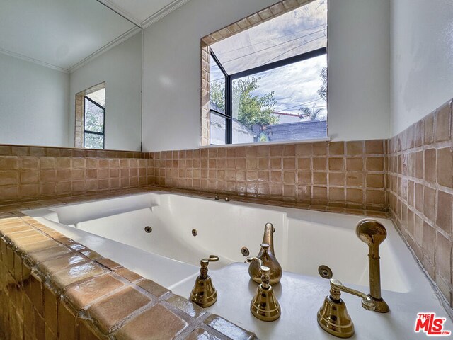 bathroom featuring ornamental molding and tiled tub