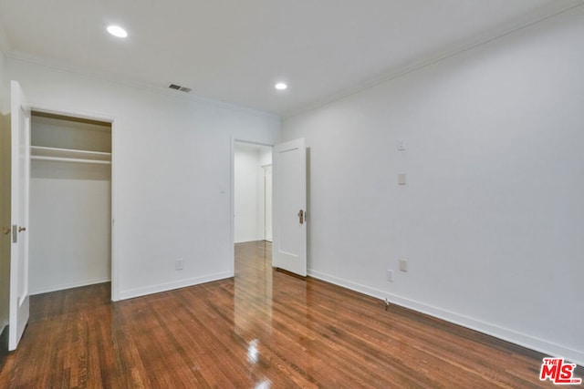 unfurnished bedroom with a closet, dark hardwood / wood-style flooring, and ornamental molding