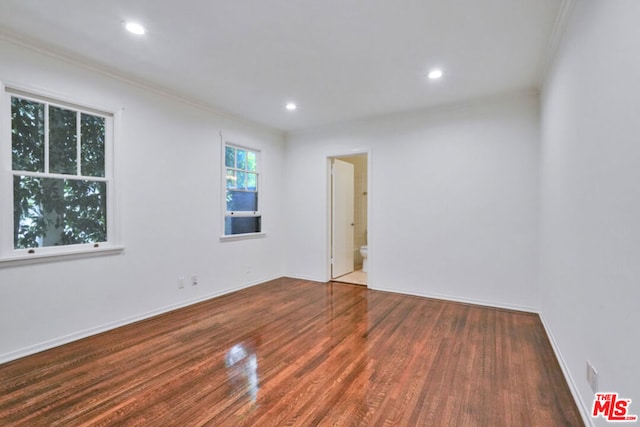 empty room with dark wood-type flooring and ornamental molding