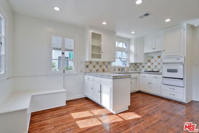 kitchen featuring white oven, white cabinets, and dark hardwood / wood-style floors