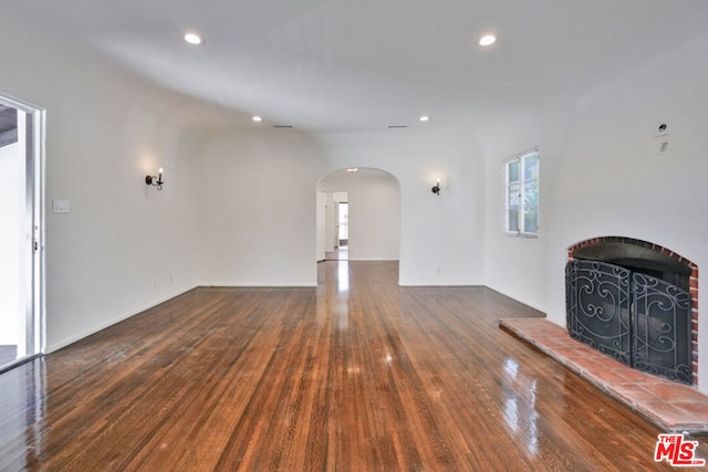 unfurnished living room featuring a tile fireplace and dark wood-type flooring