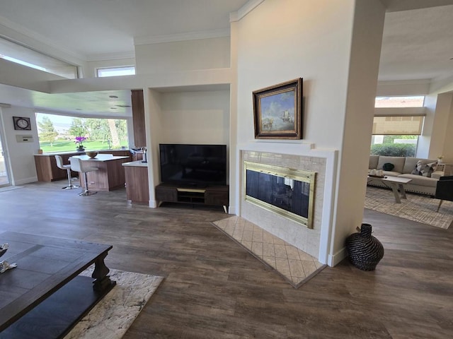 living room with dark hardwood / wood-style flooring, ornamental molding, and a tile fireplace