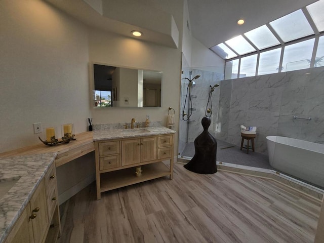 bathroom with vanity, a skylight, hardwood / wood-style flooring, tile walls, and shower with separate bathtub