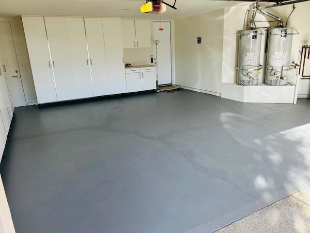 garage featuring strapped water heater, a garage door opener, and gas water heater