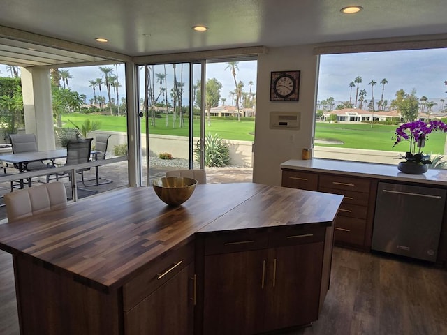 kitchen with stainless steel dishwasher, dark brown cabinets, a kitchen island, dark hardwood / wood-style flooring, and butcher block counters