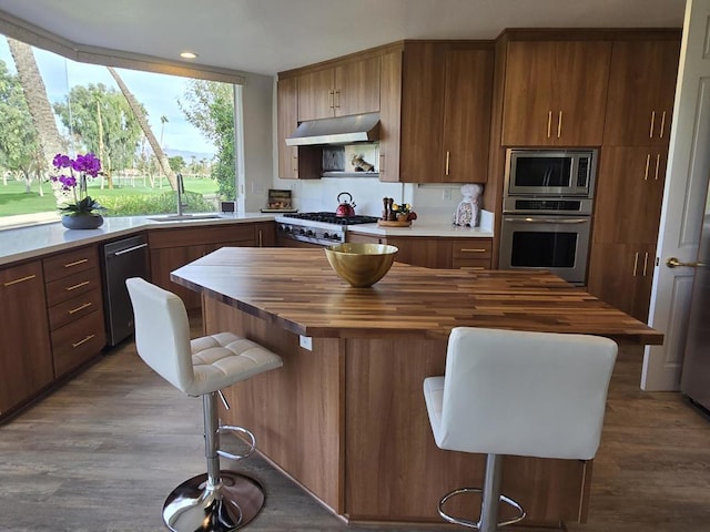 kitchen featuring wood counters, a kitchen breakfast bar, dark hardwood / wood-style flooring, stainless steel appliances, and sink