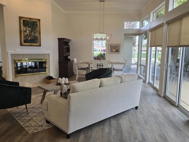 living room with crown molding, hardwood / wood-style flooring, a fireplace, a high ceiling, and a chandelier