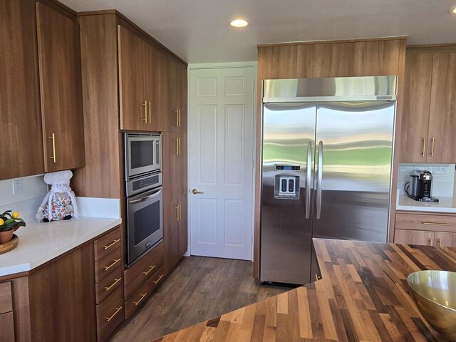 kitchen featuring built in appliances, wood counters, and dark hardwood / wood-style flooring