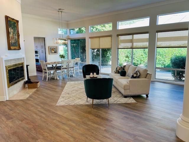 living room featuring hardwood / wood-style flooring, a healthy amount of sunlight, ornamental molding, and a tile fireplace