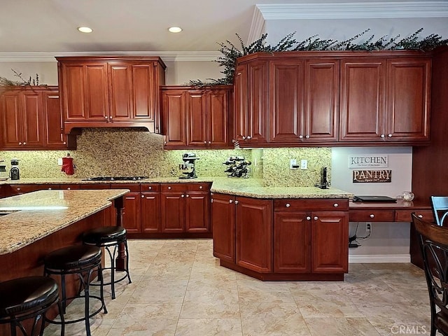 kitchen with light stone countertops, backsplash, ventilation hood, crown molding, and a breakfast bar area