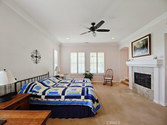 bedroom with light carpet, a fireplace, ceiling fan, and ornamental molding