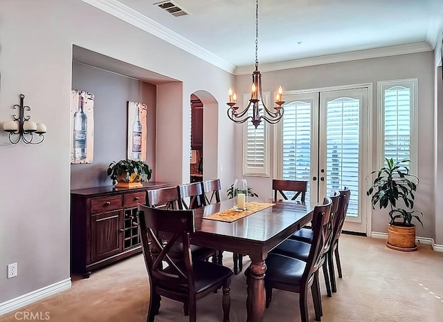 carpeted dining room with a chandelier, french doors, and ornamental molding