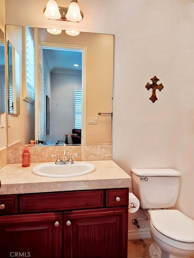 bathroom with vanity, toilet, and ornamental molding