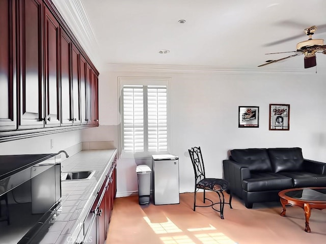 kitchen with ceiling fan, tile counters, sink, fridge, and ornamental molding