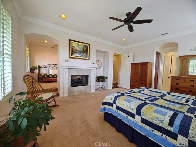 bedroom with a tile fireplace, light colored carpet, ceiling fan, and crown molding