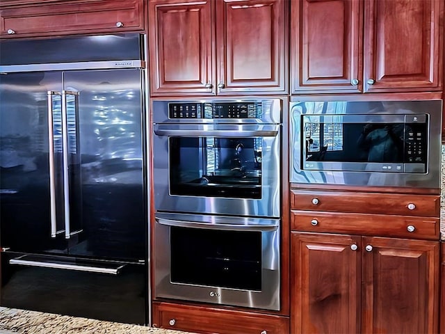 kitchen featuring built in appliances and light stone countertops