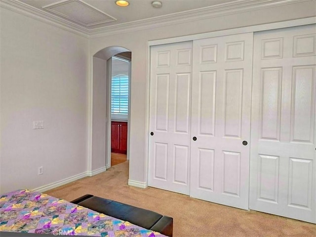 carpeted bedroom with crown molding and a closet