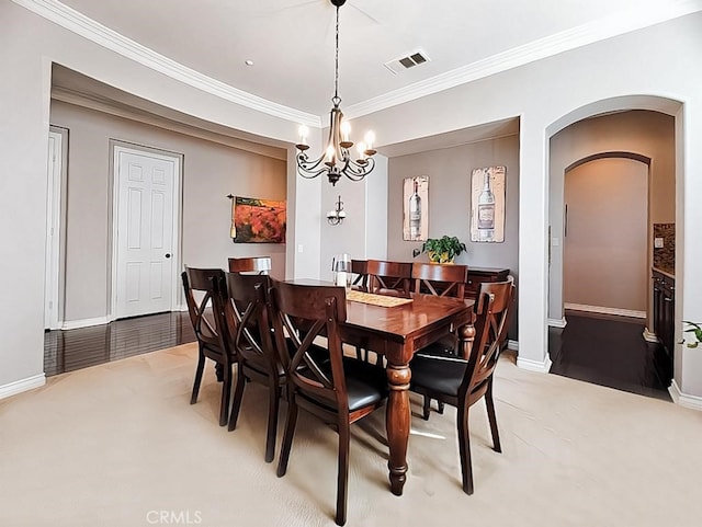 dining space featuring hardwood / wood-style flooring, ornamental molding, and an inviting chandelier