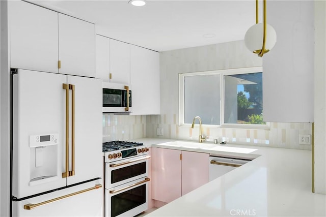 kitchen with backsplash, high quality appliances, sink, and white cabinetry