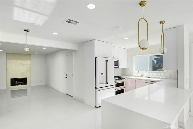 kitchen featuring sink, premium appliances, a premium fireplace, backsplash, and decorative light fixtures