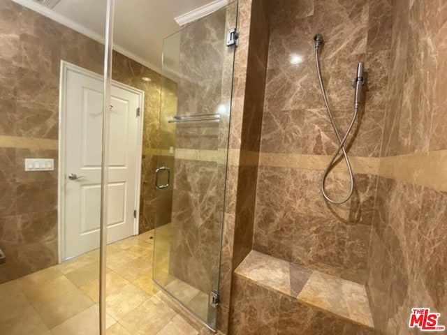 bathroom featuring ornamental molding and a shower with door