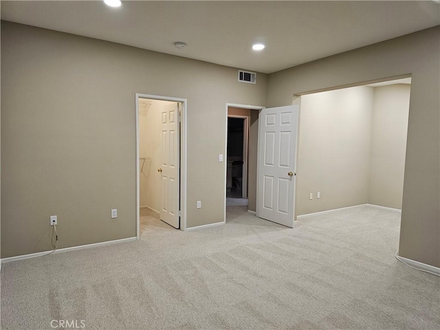 unfurnished bedroom featuring light colored carpet, a spacious closet, and a closet