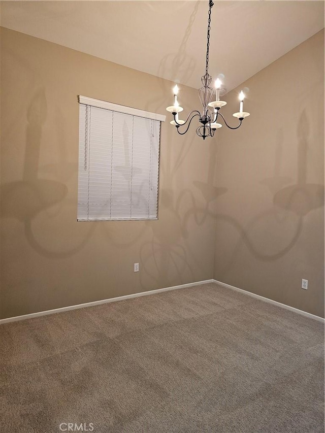 carpeted spare room featuring a notable chandelier