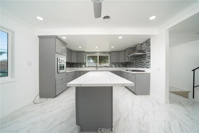 kitchen with a center island, stainless steel oven, backsplash, wall chimney exhaust hood, and gray cabinets