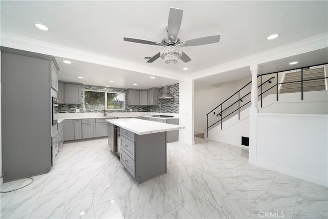 kitchen featuring gray cabinetry, a center island, stainless steel oven, wall chimney exhaust hood, and tasteful backsplash