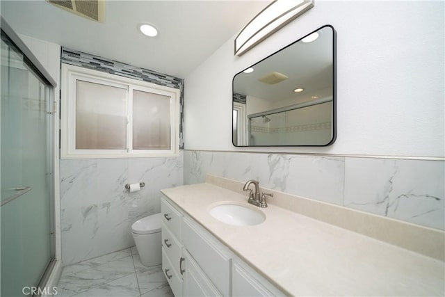 bathroom featuring vanity, toilet, tile walls, and a shower with shower door