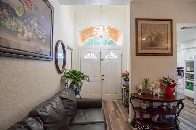 foyer entrance featuring hardwood / wood-style floors, a notable chandelier, and a high ceiling