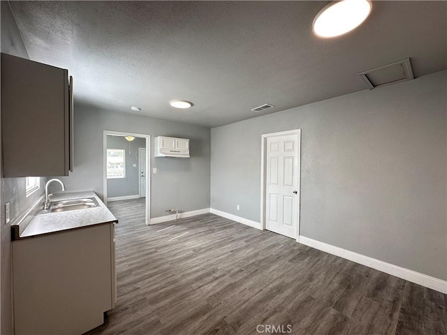 kitchen with a textured ceiling, white cabinets, sink, and dark wood-type flooring