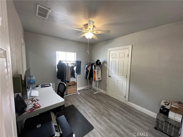 home office featuring hardwood / wood-style floors, ceiling fan, and a textured ceiling