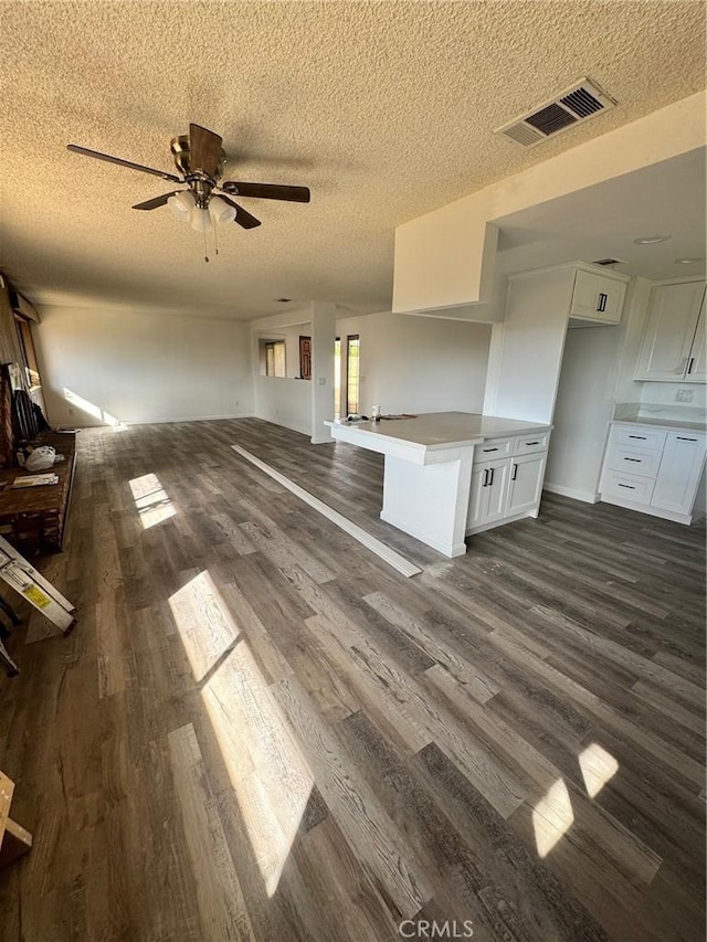 unfurnished living room featuring ceiling fan, dark hardwood / wood-style floors, and a textured ceiling