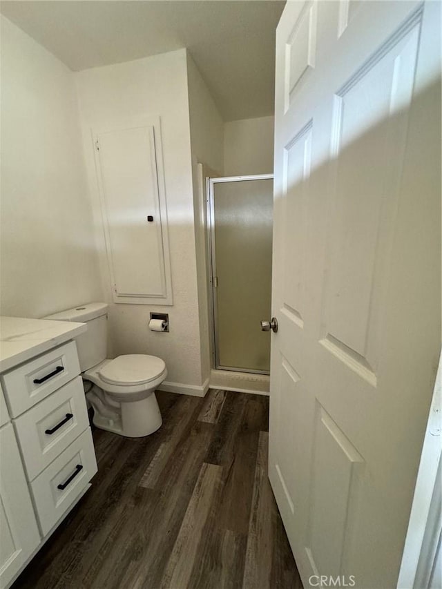 bathroom with wood-type flooring, toilet, walk in shower, and vanity