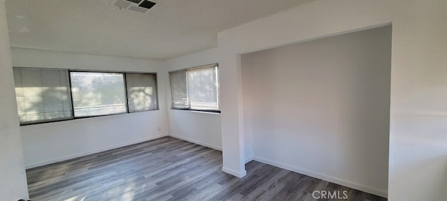 unfurnished room featuring a healthy amount of sunlight and dark hardwood / wood-style floors