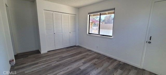 unfurnished bedroom featuring a closet, a textured ceiling, and dark hardwood / wood-style flooring