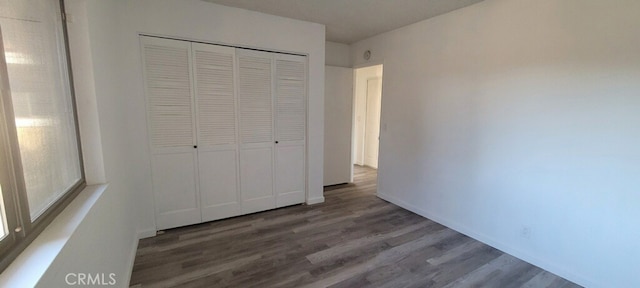 unfurnished bedroom featuring dark hardwood / wood-style floors and a closet