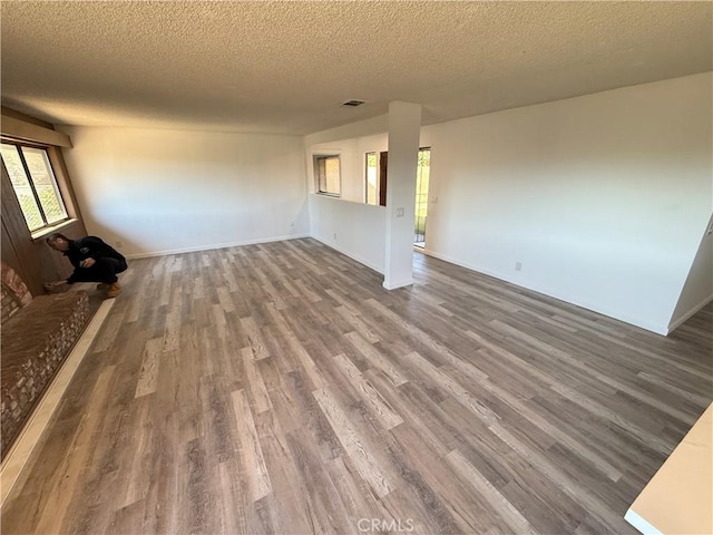 unfurnished living room featuring visible vents, a textured ceiling, and dark wood-style floors