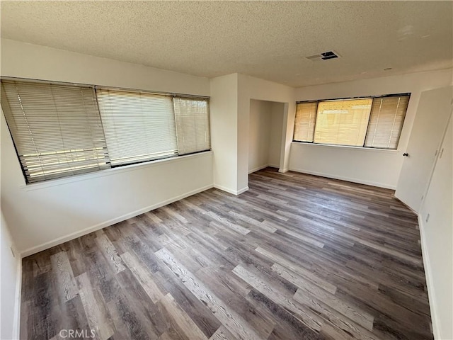 unfurnished bedroom featuring visible vents, baseboards, wood finished floors, a closet, and a textured ceiling