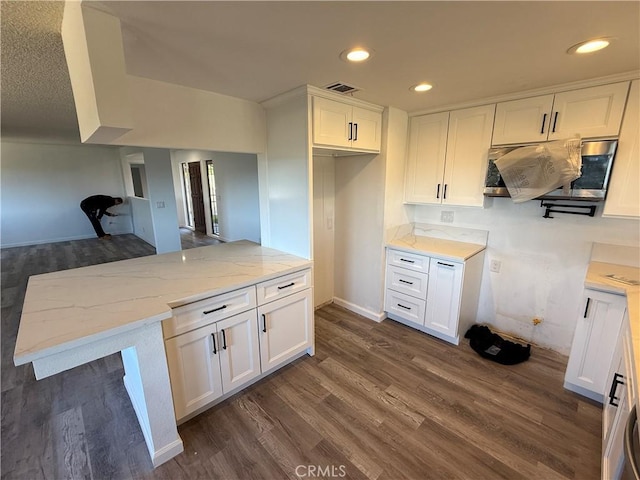 kitchen featuring dark wood-style floors, light stone countertops, and white cabinets