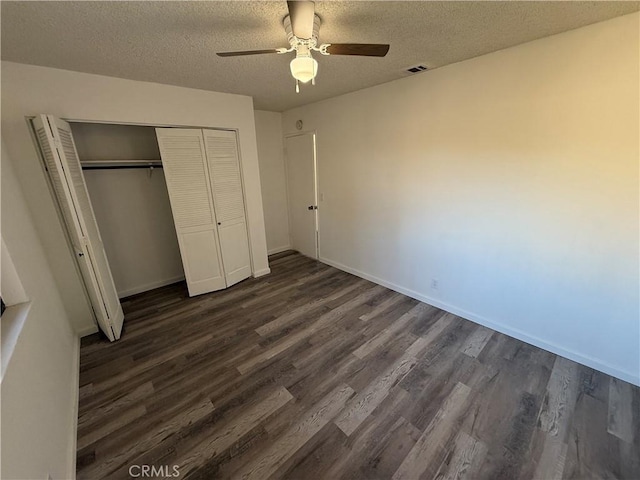 unfurnished bedroom featuring dark wood-style floors, baseboards, visible vents, a closet, and a textured ceiling