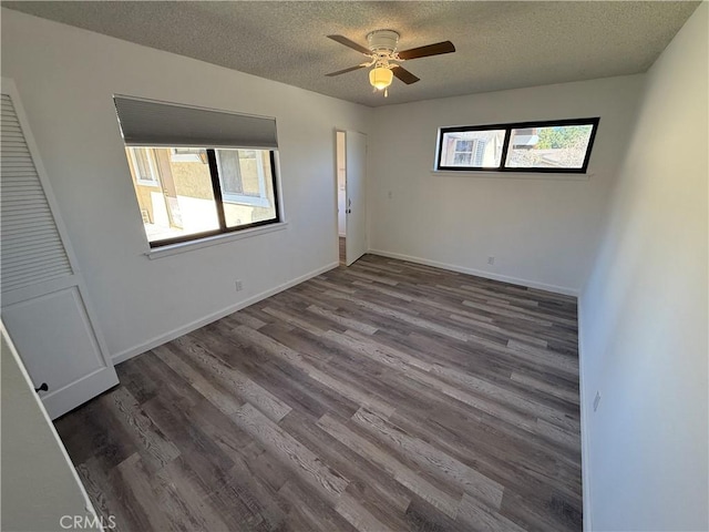 empty room featuring baseboards, plenty of natural light, a textured ceiling, and wood finished floors