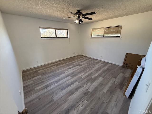 spare room with ceiling fan, a textured ceiling, baseboards, and wood finished floors