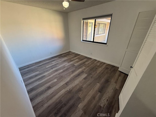 unfurnished bedroom featuring dark wood finished floors, ceiling fan, a textured ceiling, and baseboards