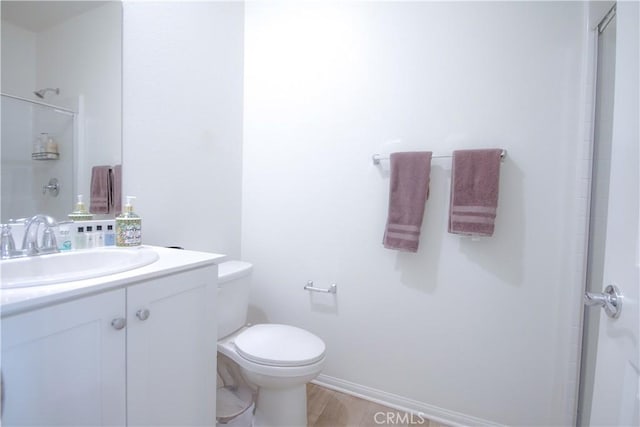 bathroom featuring vanity, wood-type flooring, an enclosed shower, and toilet