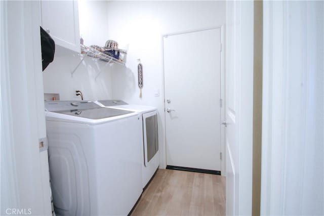 clothes washing area with light wood-type flooring and separate washer and dryer