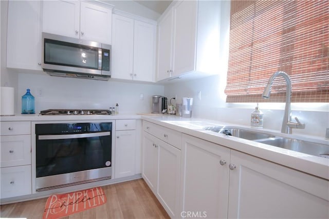 kitchen featuring white cabinets, appliances with stainless steel finishes, light hardwood / wood-style flooring, and sink