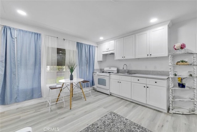 kitchen featuring white range with gas cooktop, white cabinetry, sink, and light hardwood / wood-style floors